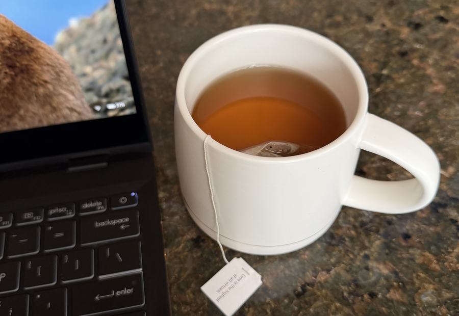 Tea beside an open laptop in morning light